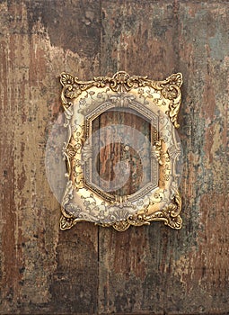 Baroque golden frame on wooden background. Grunge texture