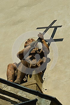 Baroque looking statue of small angel holding iron cross, located above front entrance door of Church Of Saint Michael in Skalica,