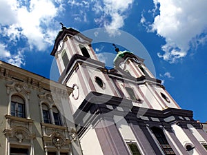 Baroque style double church towers with clocks and green copper metal roofs. blue sky.