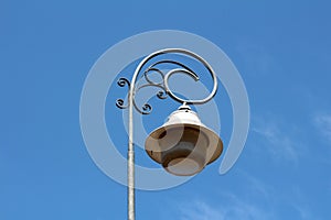 Baroque style street lamp with wrought iron decoration mounted on tall metal pole