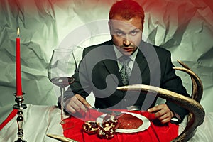 Baroque supper of blue blood aristocrat a-la Hannibal Lecter. Handsome man eating fresh meat at vintage restaurant. Baroque