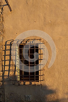 Barred window in an ancient building, sunset light and shadows