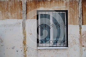 Barred window in a concrete wall with rusty smudges, background
