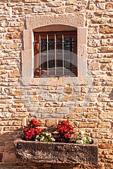 Barred window and a cut stone planter with flowers