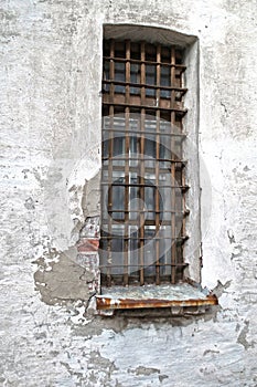 Barred window in a peeling brick wall.