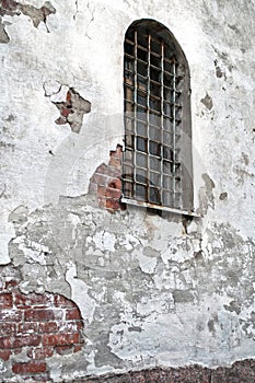 Barred window in a peeling brick wall.