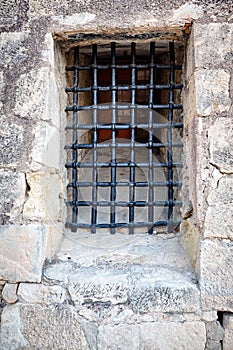 Barred window in the stone wall of the castle Santa Barbara, Alicante, Spain