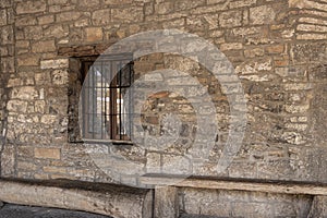 barred window in a stone wall in the village of ainsa