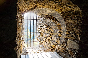 Barred window walled in an old natural stone wall