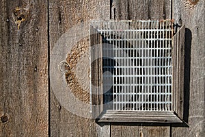 Barred window in a wooden wall.