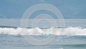 A barreling wave in the blue sea crashing onto the surfers on a sunny day.