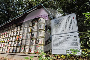 Barrels of Sake wrapped in Straw stacked on shelf with description board