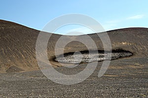 Barren dry landscape around GrÃÂ¡brÃÂ³k with spot of melted ice on black hill against blue sky, Iceland photo