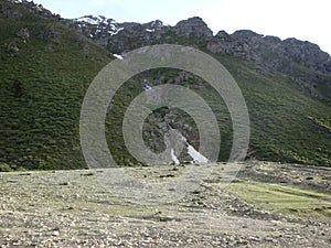 A barren green meadow under the mountain