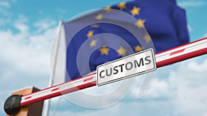 Barrier gate with CUSTOMS sign being closed with flag of the EU as a background. European Border closure or protective photo