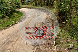 barrier with a no entry sign on a dirt road, detour - written in Spanish on the sign