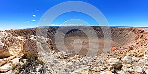 Meteor crater, Arizona. Rocks and plants in foreground. Observation platform visible. Sky in the distance. photo