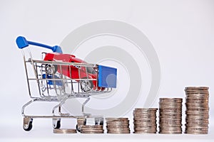 A barrow small shopping cart with coins on a white background for economizing  buying cars Concept of economizing and buying cars