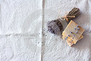 Bars of handmade soap and dry lavender flower on linen background