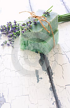 Bars of handmade soap with lavender flowers over white wood grunge background.