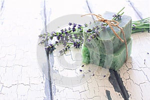 Bars of handmade soap with lavender flowers over white wood grunge background.