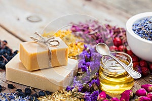 Bars of homemade soaps, honey or oil and heaps of healing herbs photo