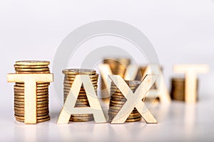 Bars stacked from coins on a white table. TAX and VAT lettering with wooden letters based on coins