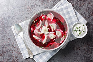 Barszcz z uszkami beetroot soup, borsch with small dumplings closeup on the plate. Horizontal top view