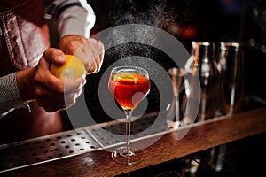 Bartender is adding lemon zest to the cocktail at bar counter. Selective focus