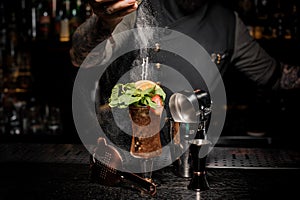 Bartender adding powder to a fresh summer cocktail with fruits