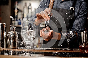 Bartender splitting a piece of ice at a bar counter photo