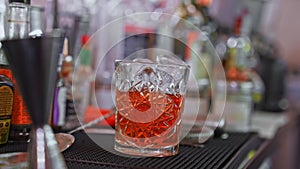 Bartender with cocktail and orange peel preparing cocktail at the bar.