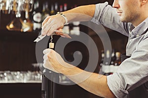 Bartender concentrated on uncork of elite drink at bar counter.