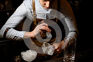 Bartender crushes piece of ice with crusher