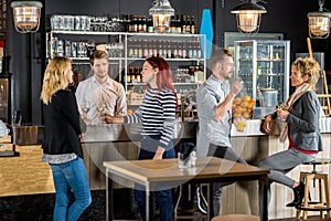 Bartender With Customers Having Drinks In Bar