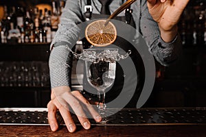 Bartender decorating a clear alcoholic drink with a slice of lemon