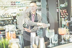 Bartender doing flair inside cruise american bar - Barman at work performing freestyle with bottle and shaker - Focus on man face