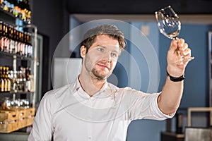 Bartender Examining Glass Of Wine In Bar