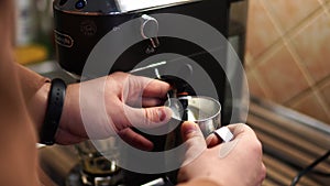 Bartender frothing milk in a milk jug with a nozzle on a coffee machine