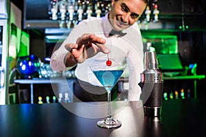 Bartender garnishing cocktail with cherry photo