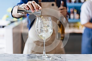 Bartender gently pour alcohol and soda in a wine glass with ice for making cocktail