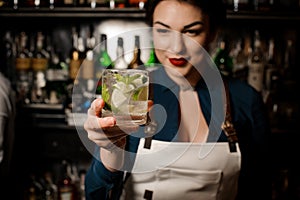 Bartender girl holding an fresh cocktail with lime and mint