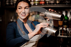 Bartender girl holding two steel cocktail shakers