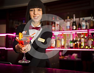 Bartender girl at night club counter offering coctail barmaid