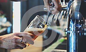 Bartender hand at beer tap pouring a draught beer in glass