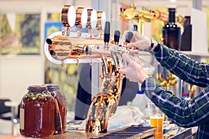 Bartender hand at beer tap pouring a draught beer in glass serving in a restaurant or pub