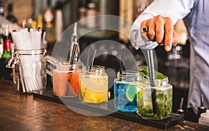 Bartender hand at multicolored fashion drinks at cocktail bar