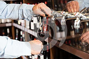 Bartender hand pouring draught red wine to glass