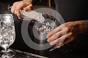 Bartender hand putting ice into the cocktail glass