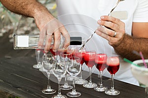 Bartender hands pouring alcohol in red cocktail
